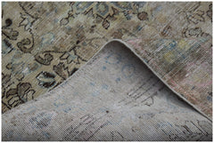 A vintage Persian Sarouk rug with a faded floral pattern and a visible cotton foundation.