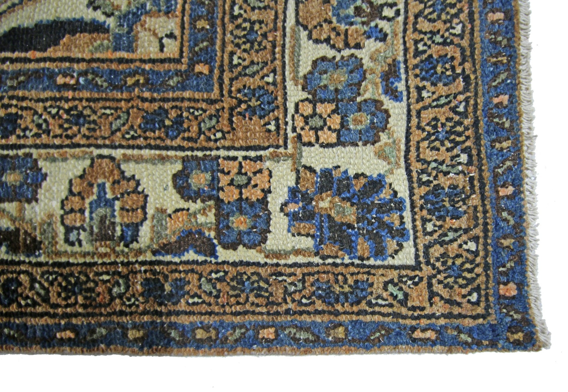 A close-up of a vintage Persian Sarouk rug featuring intricate floral patterns in blue and tan.