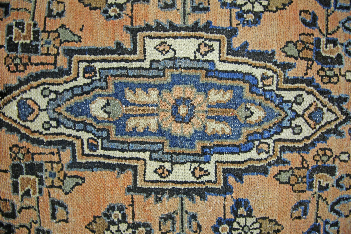 A vintage Persian Sarouk rug featuring a central blue floral medallion on an orange field.