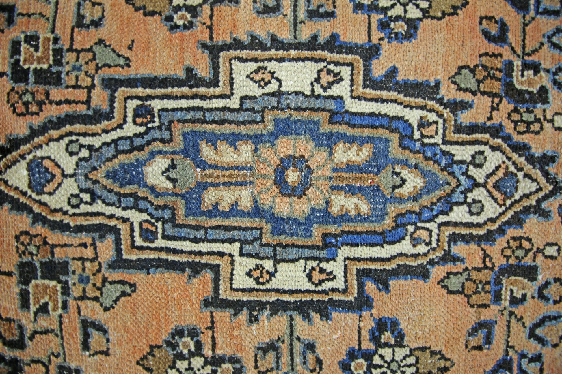 A vintage Persian Sarouk rug featuring a central blue floral medallion on an orange field.