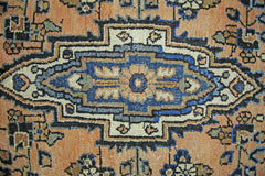 A vintage Persian Sarouk rug featuring a central blue floral medallion on an orange field.