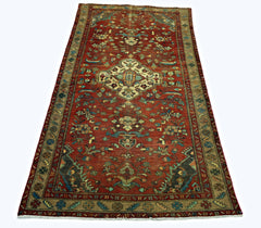 A vintage Persian Sarouk rug featuring a central floral medallion on a red field with tan borders.
