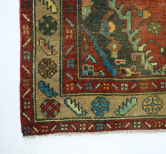 A corner view of a vintage Persian Sarouk rug featuring intricate floral patterns in wool.