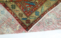 A folded vintage Persian Sarouk rug featuring intricate floral patterns in red, blue, and tan.