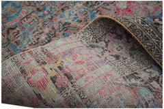 A handwoven vintage Persian rug with a faded floral pattern and visible abrash color variations.