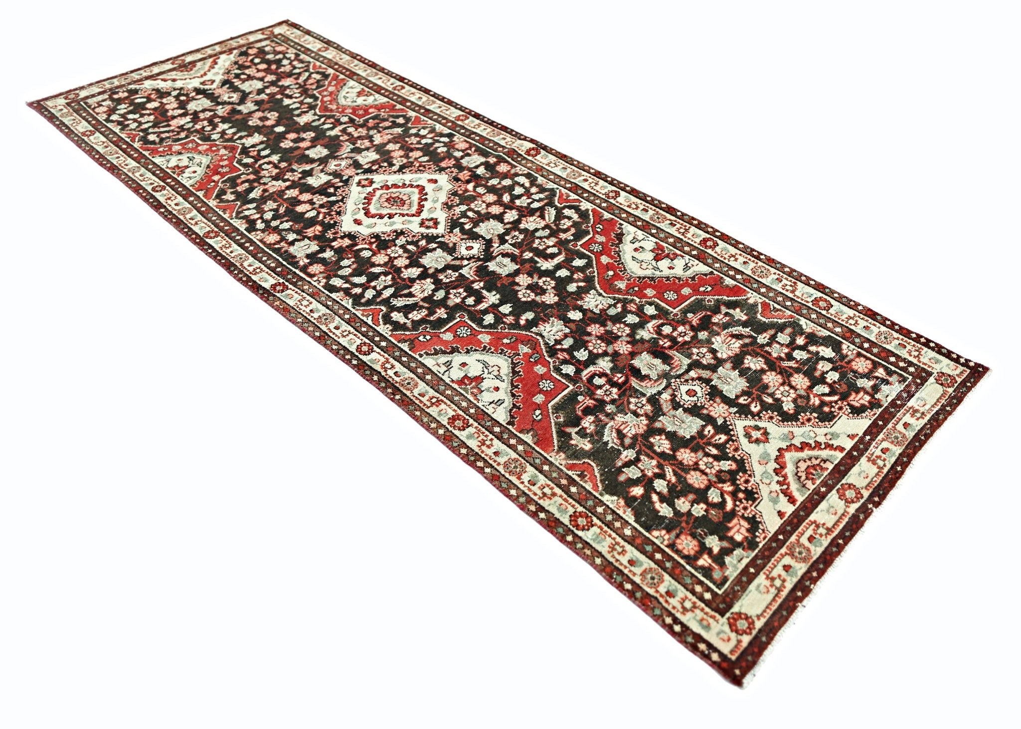 A vintage Persian Sarouk runner featuring a dark field with intricate red and cream floral motifs.