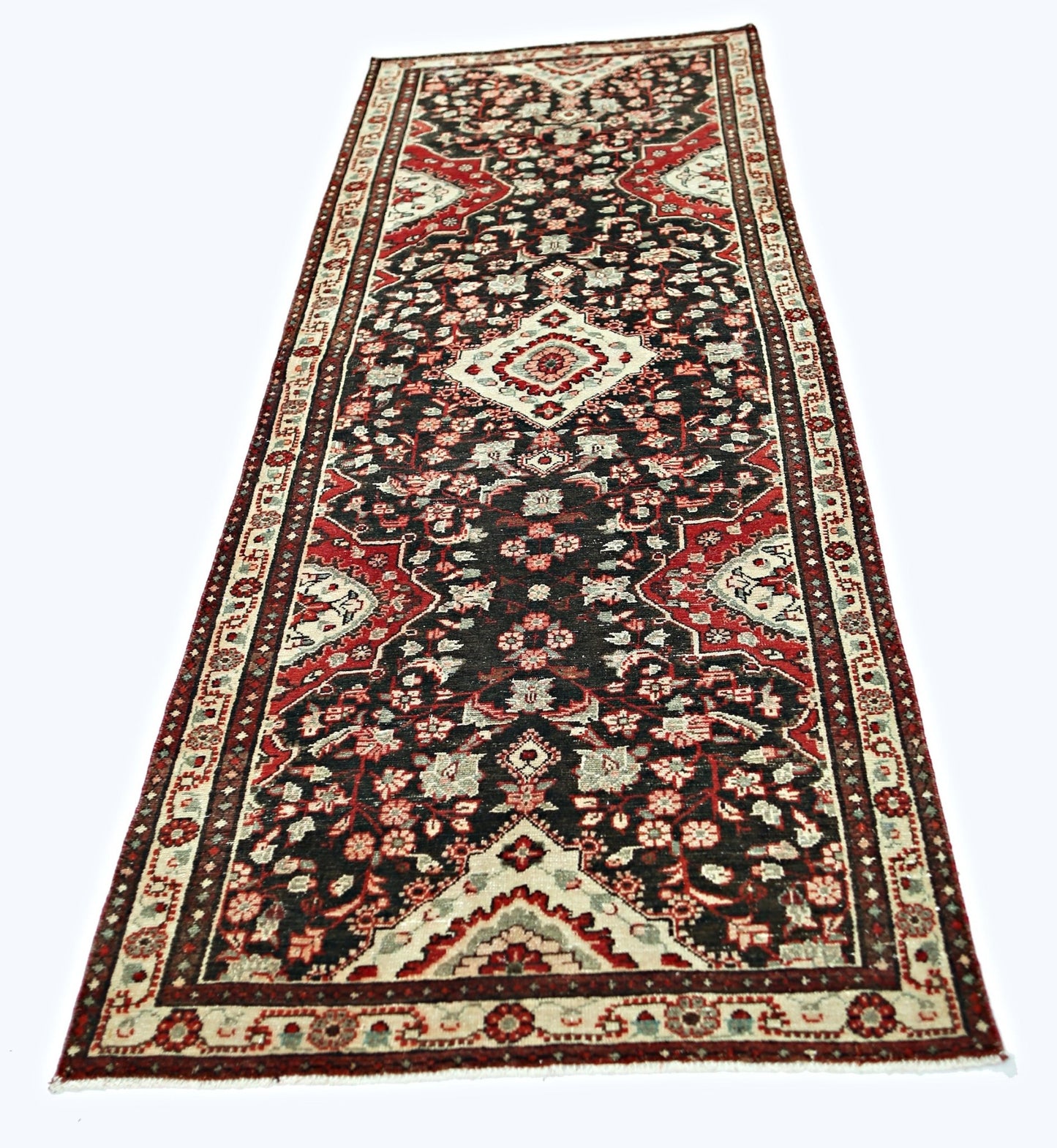 A vintage Persian Sarouk runner featuring a dark field with intricate red and cream floral patterns.