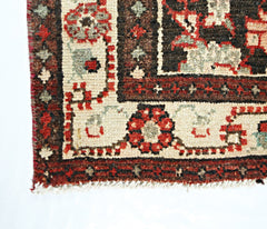 A vintage Persian Sarouk runner featuring a geometric floral pattern in red, brown, and cream.