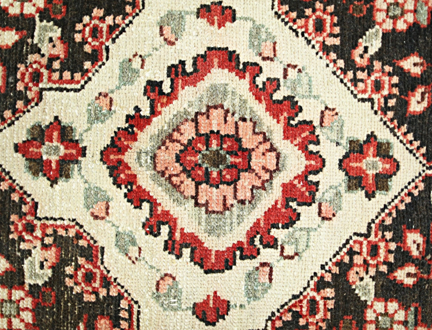 A vintage Persian Sarouk runner featuring a central floral medallion in red, pink, and cream tones.