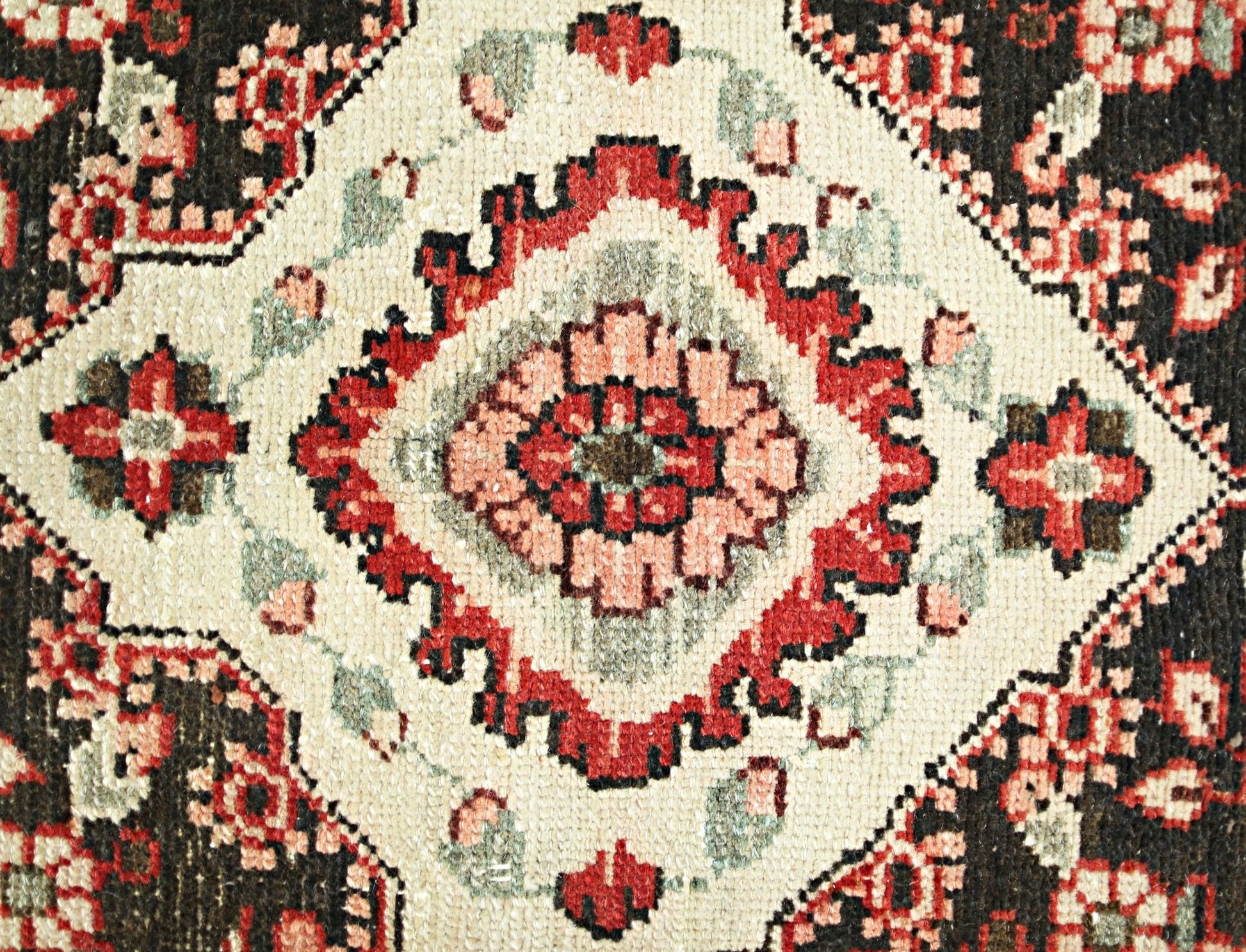 A vintage Persian Sarouk runner featuring a central floral medallion in red, pink, and cream tones.