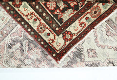A corner of a vintage Persian Sarouk runner showing its intricate floral pattern and wool weave.