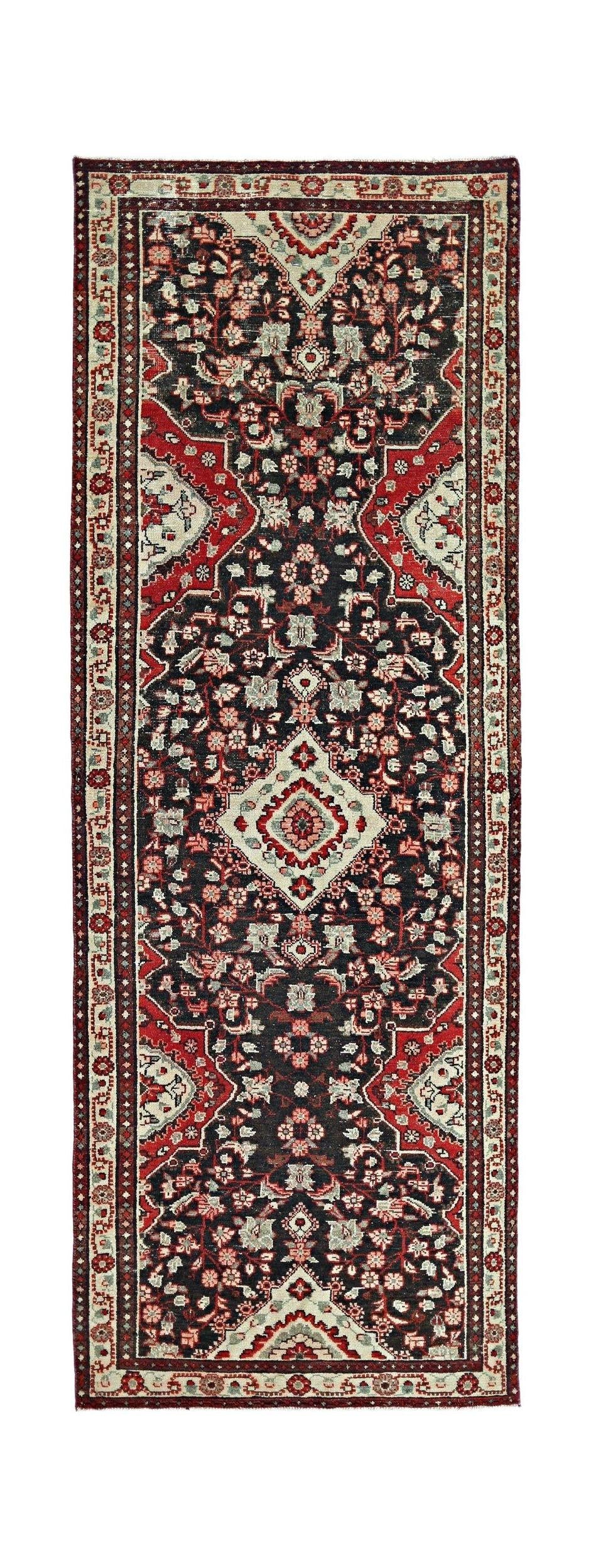 A vintage Persian Sarouk runner featuring a dark field with intricate floral patterns in red.