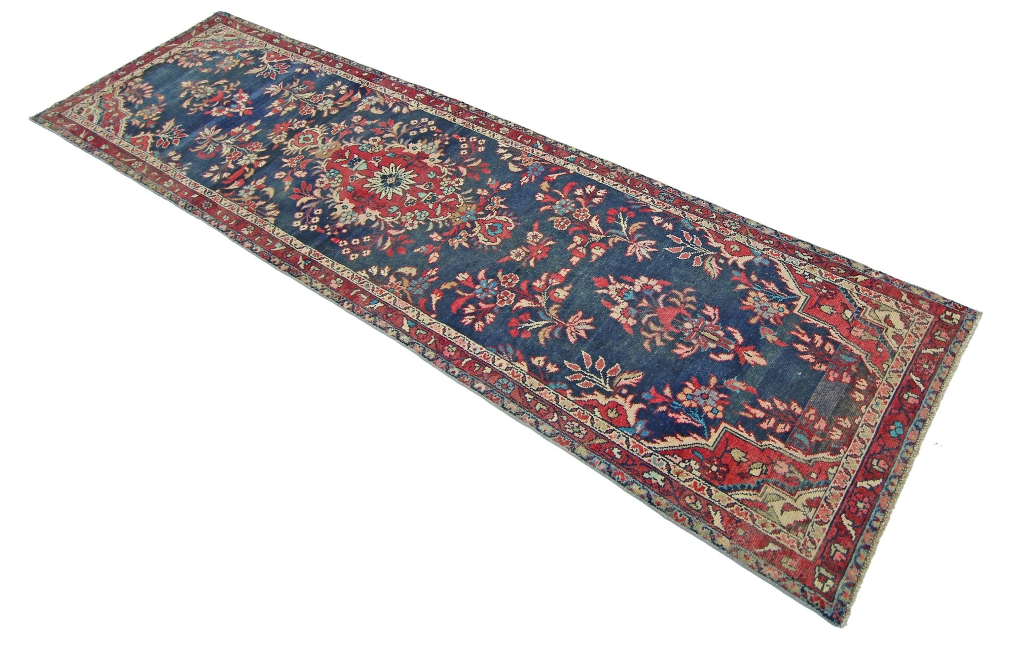 A vintage Persian Sarouk runner featuring a floral pattern in red and blue on a dark blue field.