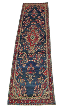 A vintage Persian Sarouk runner featuring a floral pattern in red and blue on a dark blue field.