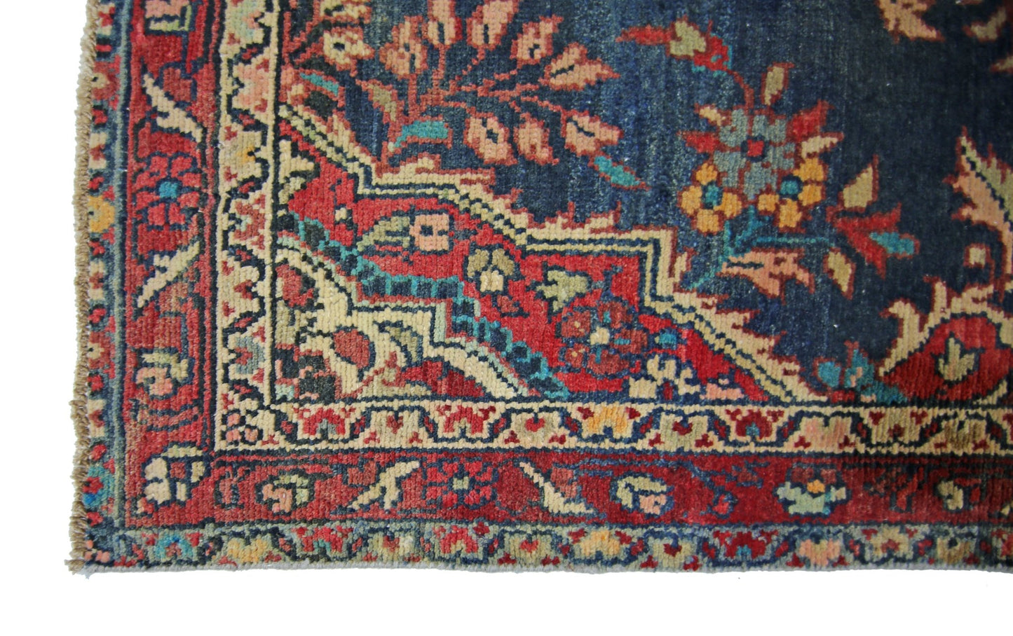 A corner view of a vintage Persian Sarouk runner featuring intricate floral patterns in red and blue.