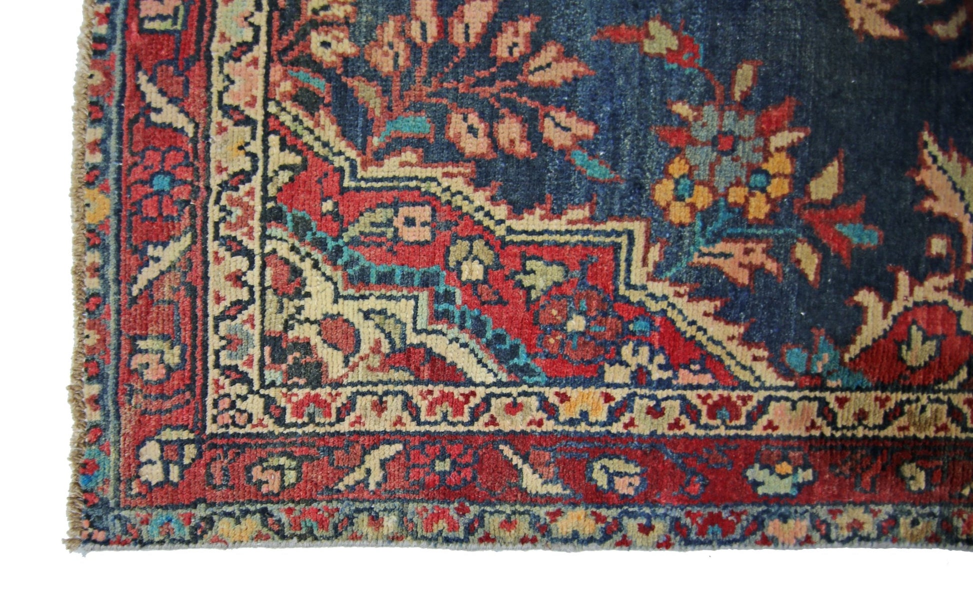 A corner view of a vintage Persian Sarouk runner featuring intricate floral patterns in red and blue.