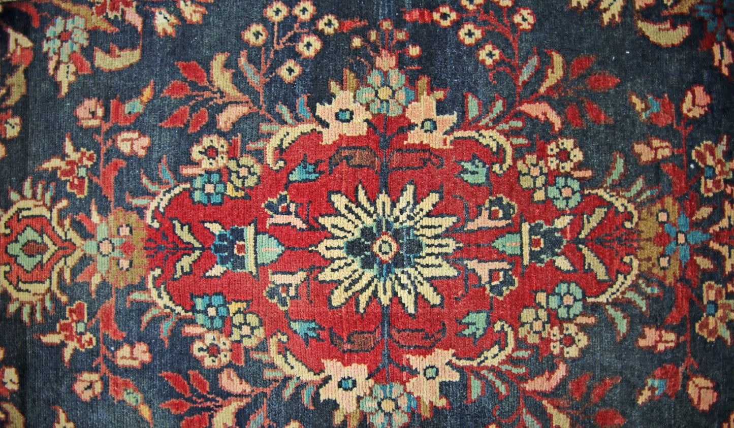 A vintage Persian Sarouk runner featuring a central floral medallion on a dark blue background.