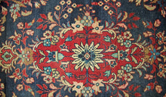 A vintage Persian Sarouk runner featuring a central floral medallion on a dark blue background.