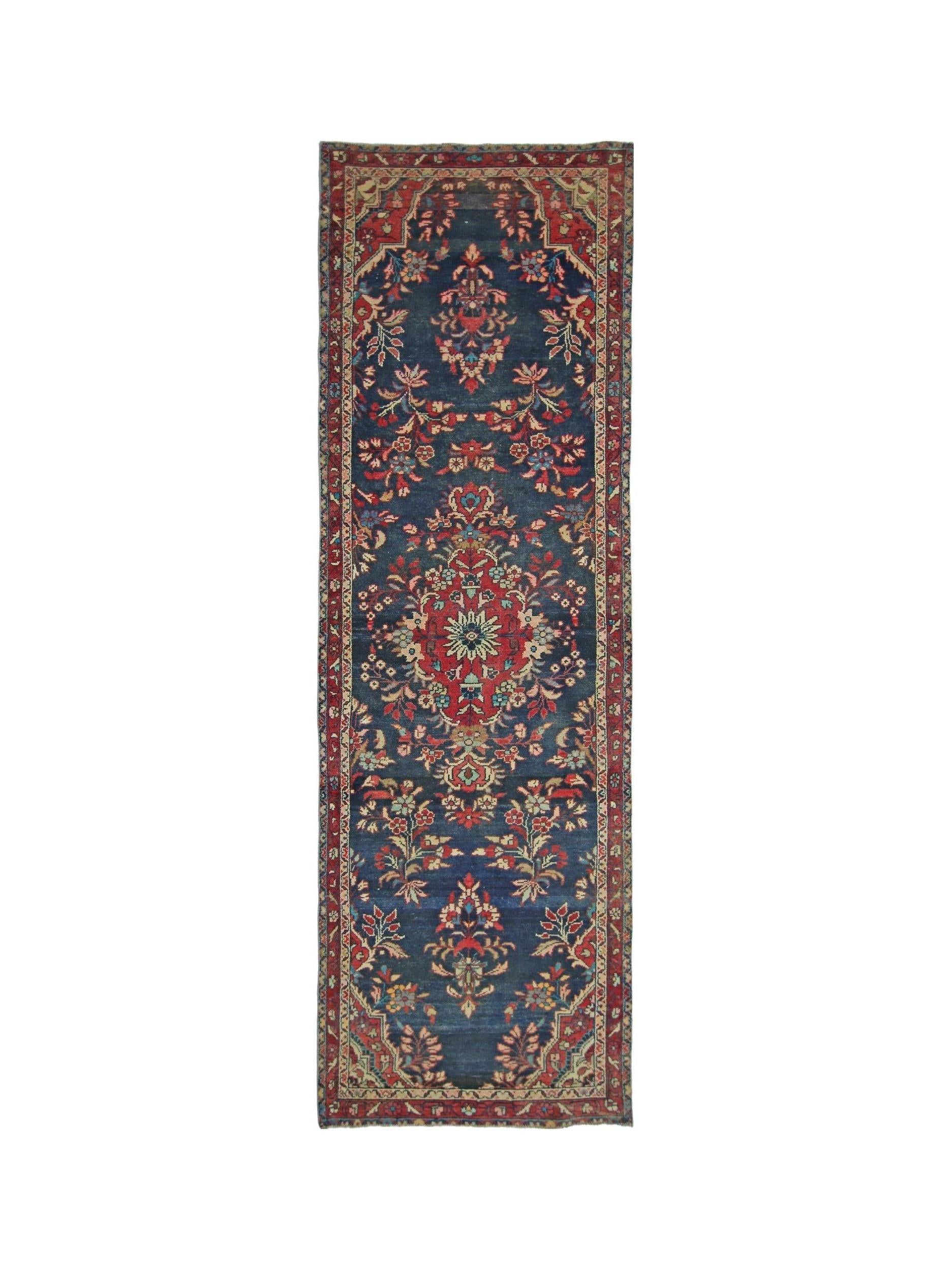 A vintage Persian Sarouk runner featuring a floral medallion pattern on a deep blue wool field.