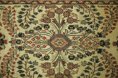 A vintage Persian Sarouk runner featuring a symmetrical floral medallion on a beige wool field.