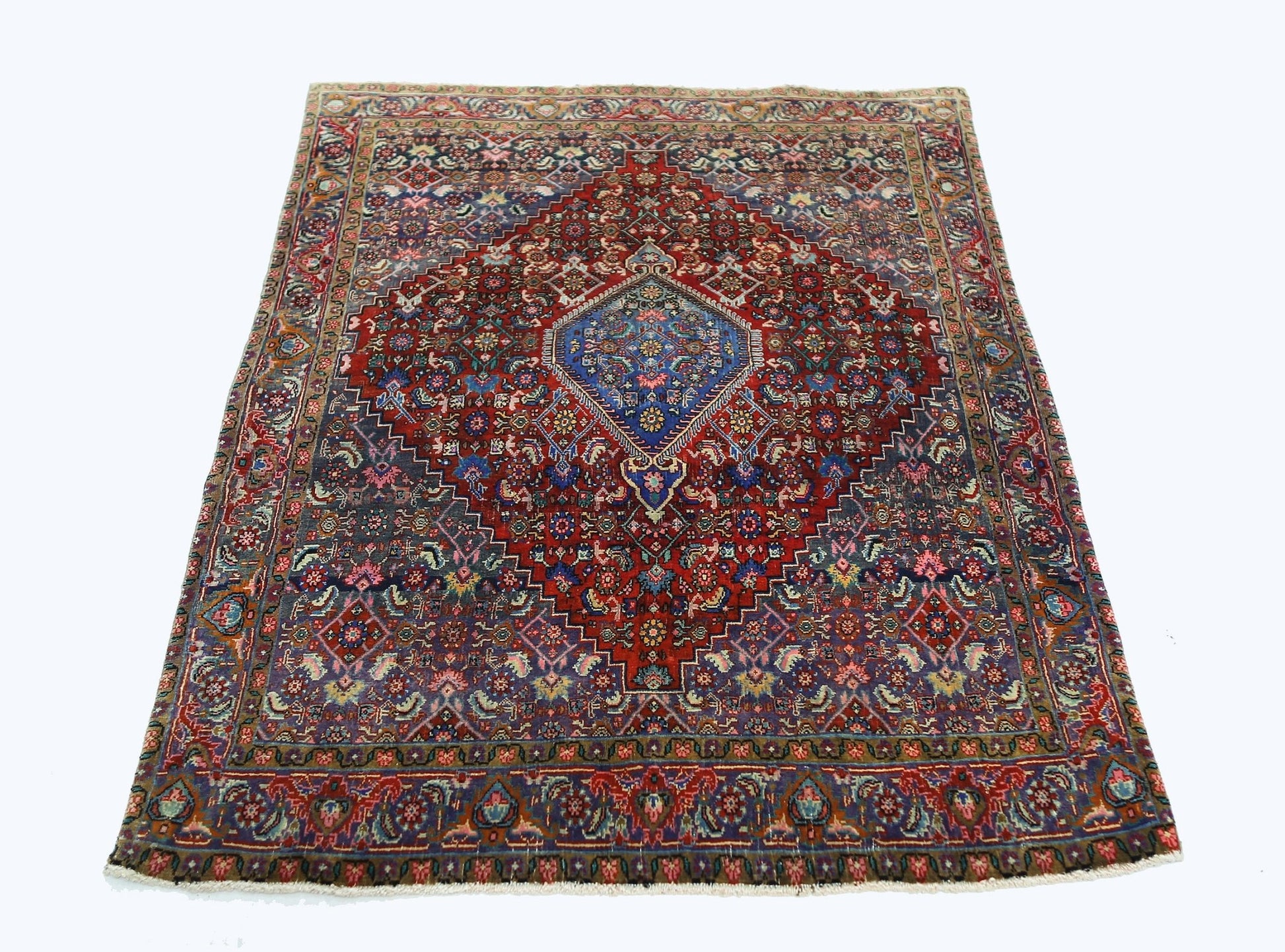 A vintage Persian Senneh rug featuring a central blue diamond medallion on a deep red field.
