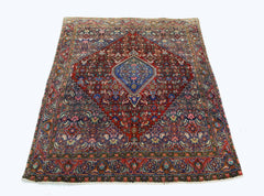 A vintage Persian Senneh rug featuring a central blue diamond medallion on a deep red field.