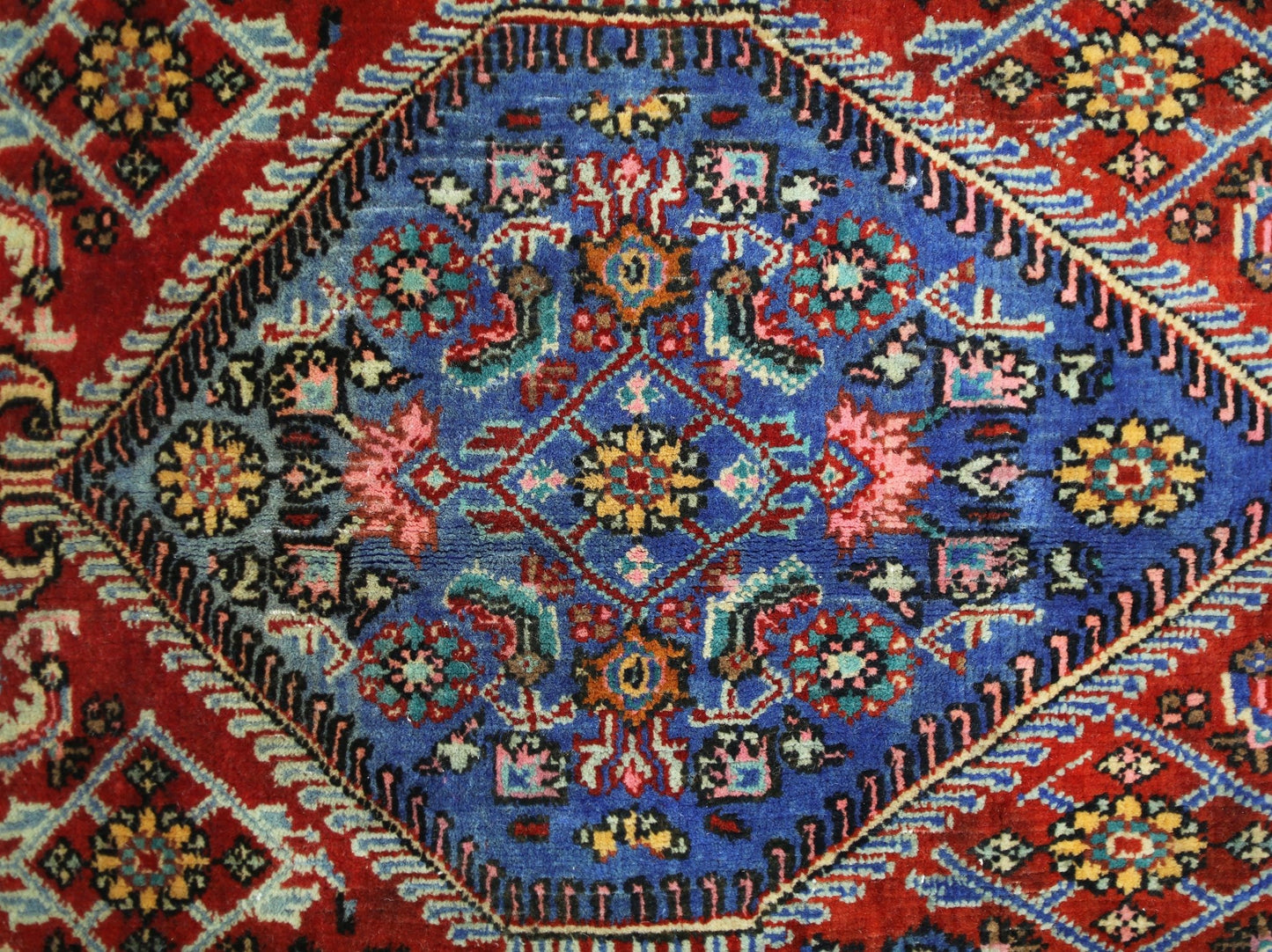 A vintage Persian Senneh rug featuring a central blue diamond medallion with intricate floral motifs.