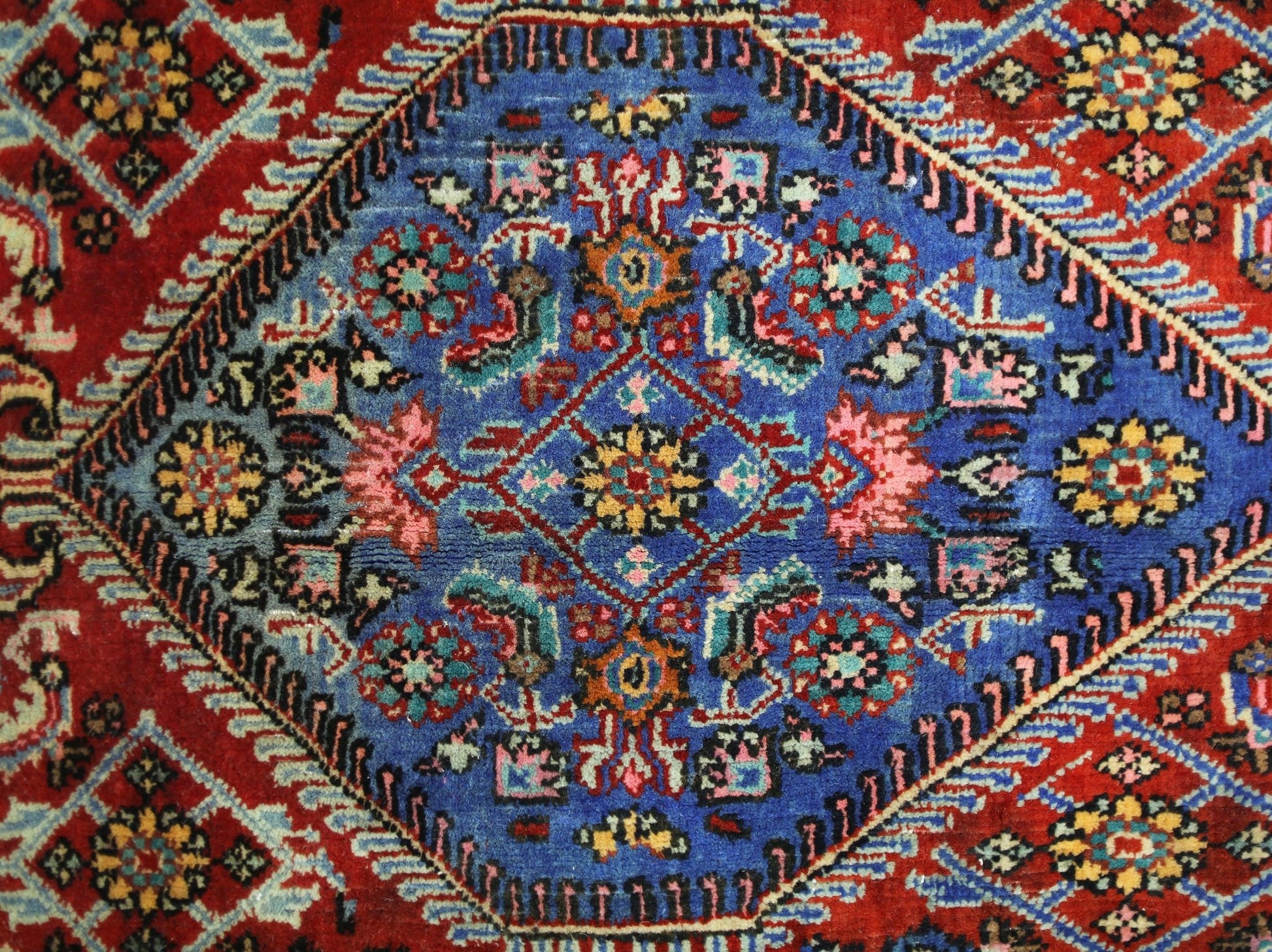 A vintage Persian Senneh rug featuring a central blue diamond medallion with intricate floral motifs.