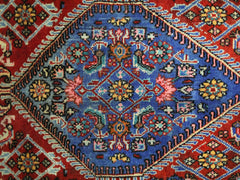A vintage Persian Senneh rug featuring a central blue diamond medallion with intricate floral motifs.
