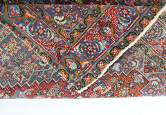 A vintage Persian Senneh rug with intricate floral patterns in red, blue, and gold tones.