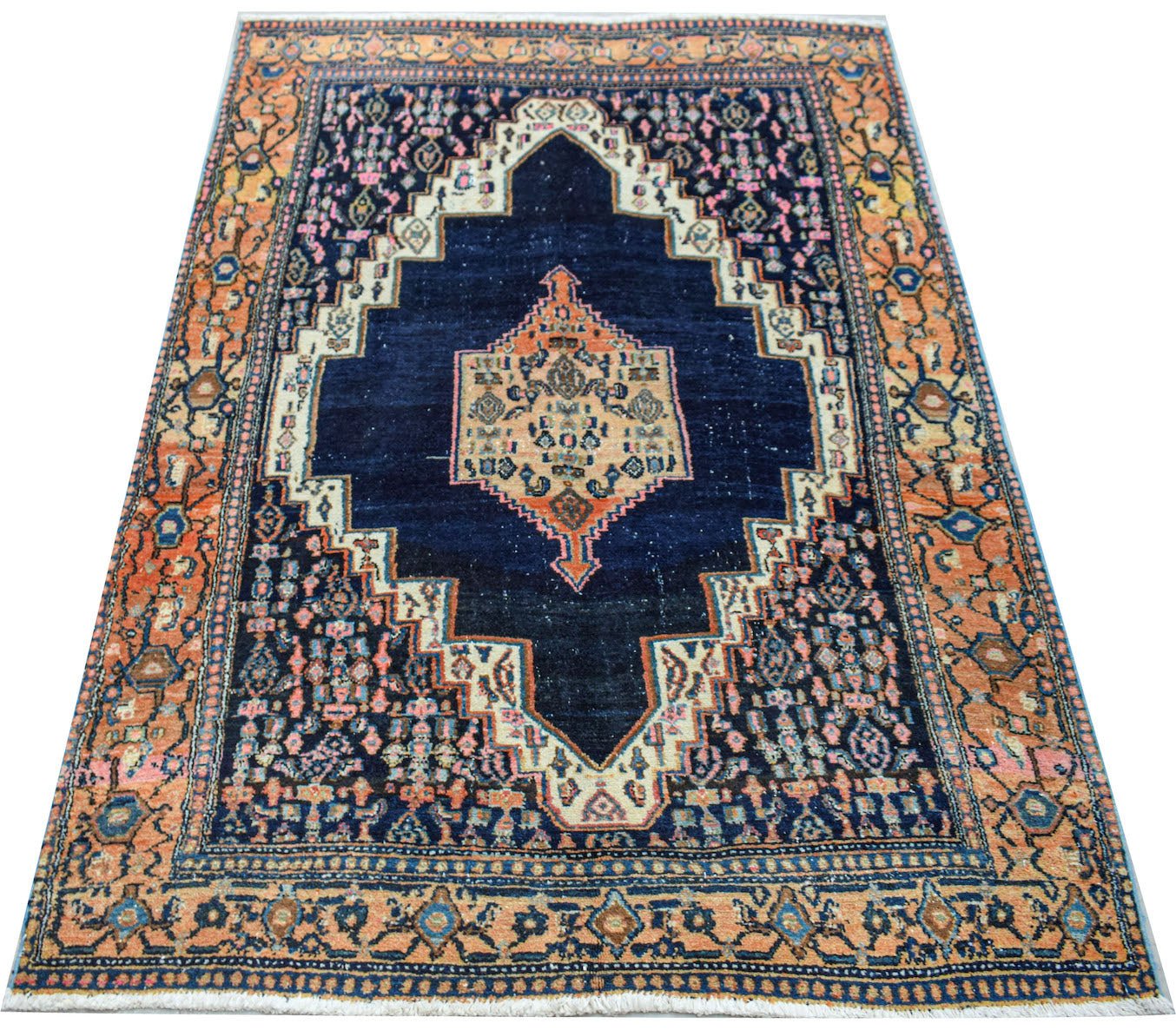 A vintage handwoven Persian rug featuring a dark blue central medallion with orange accents.