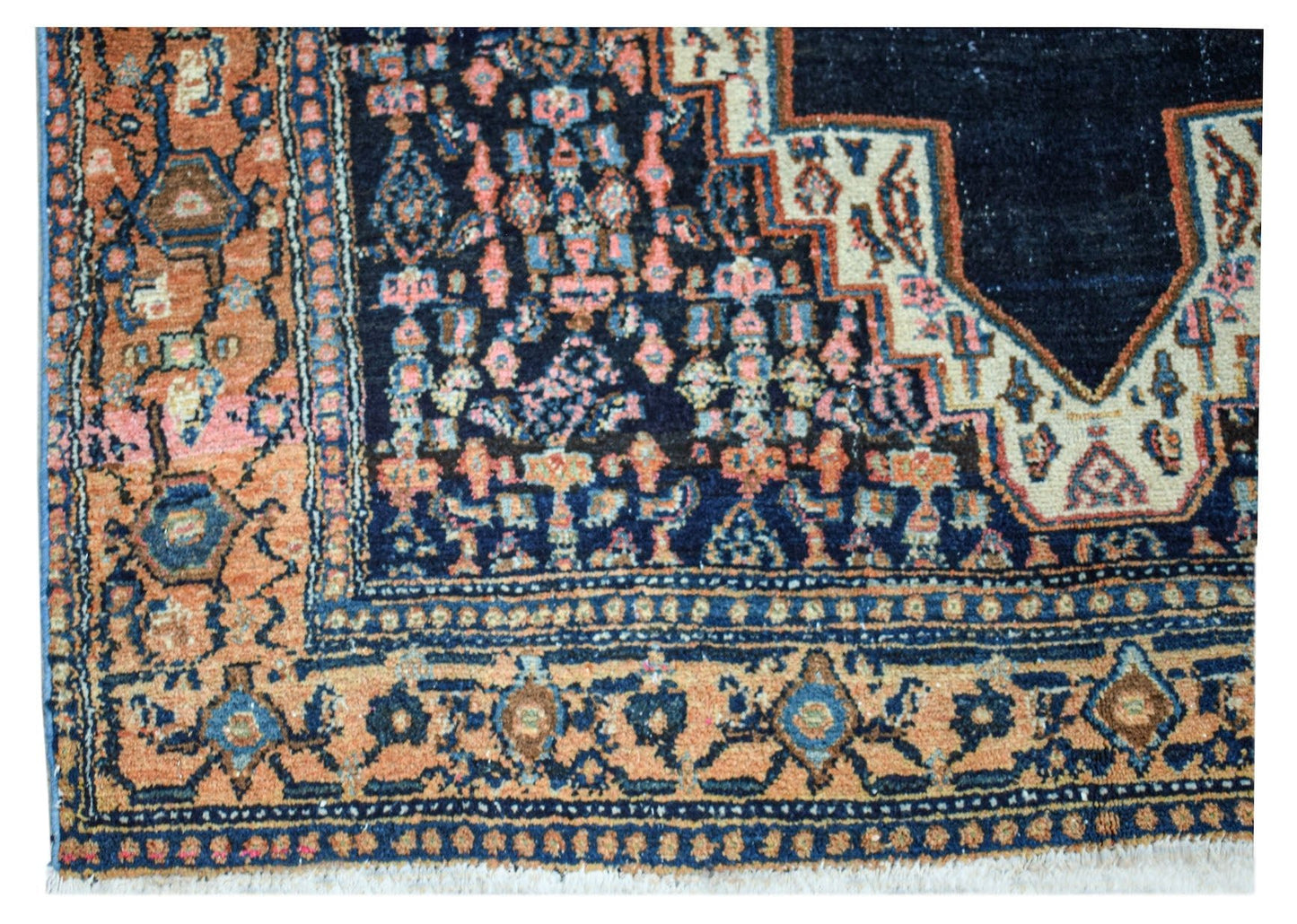 A vintage handwoven Persian rug featuring a dark blue center with intricate floral patterns.