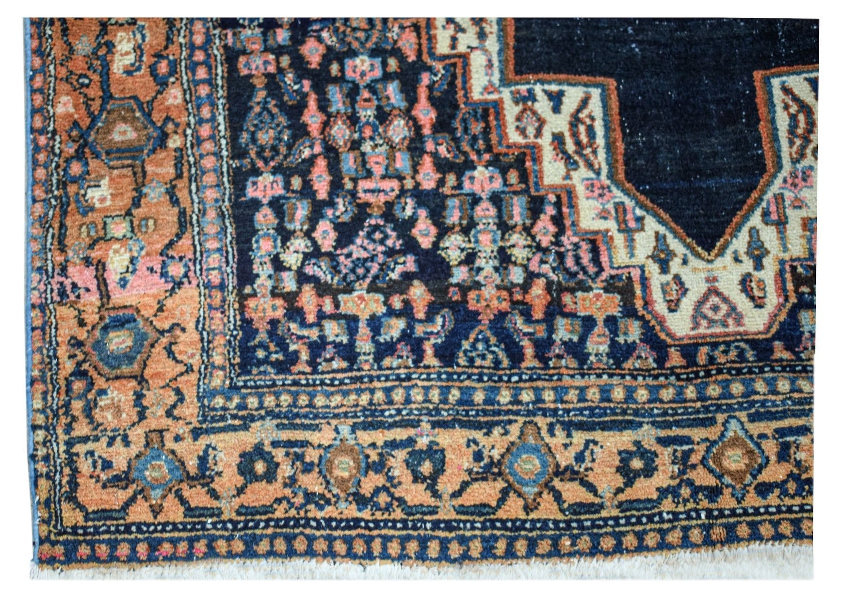 A vintage handwoven Persian rug featuring a dark blue center with intricate floral patterns.