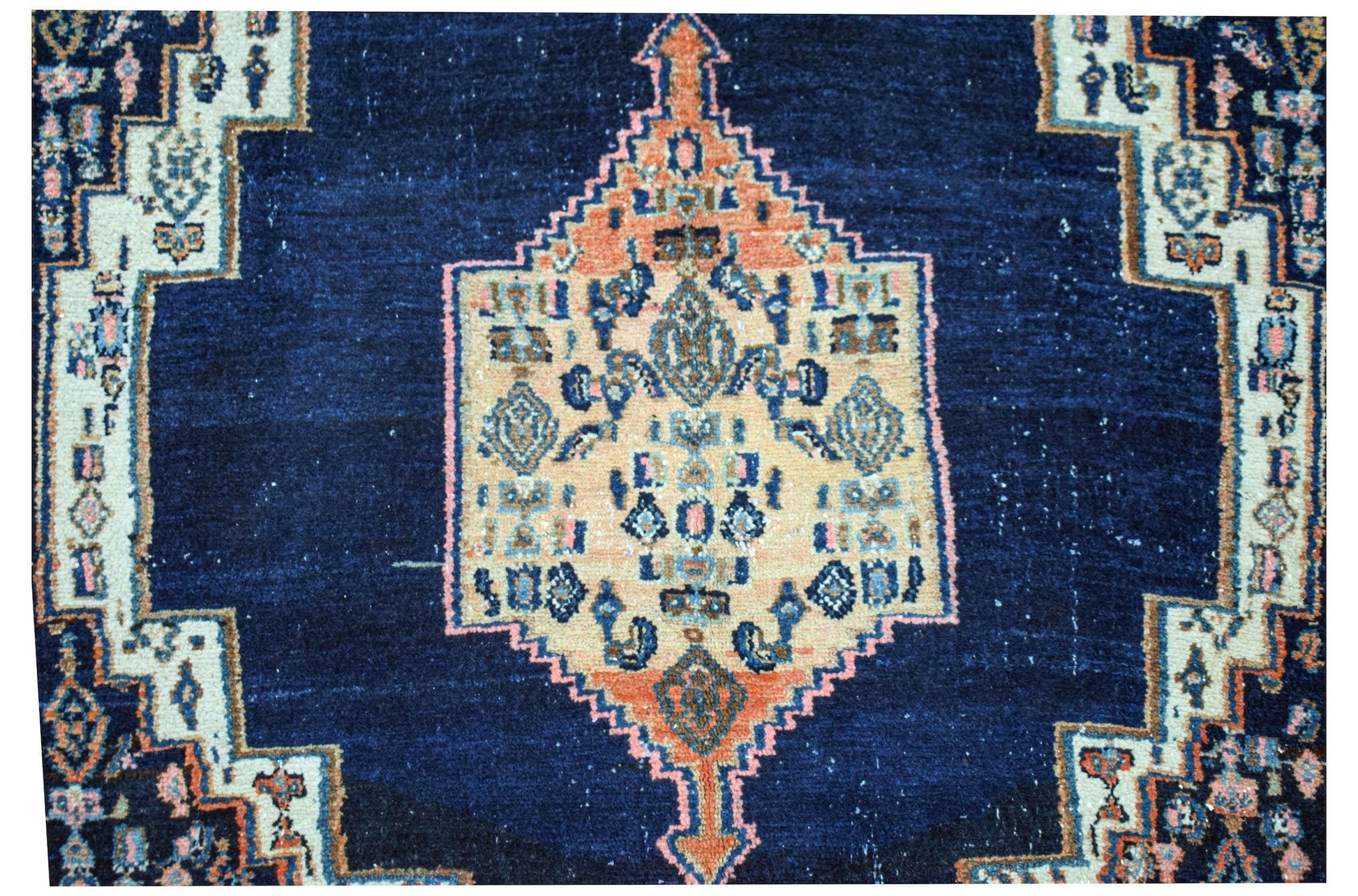 A vintage handwoven Persian rug featuring a central geometric medallion on a deep blue field.
