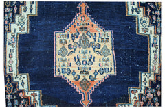 A vintage handwoven Persian rug featuring a central geometric medallion on a deep blue field.