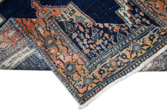 A handwoven vintage Persian rug featuring a dark blue field with orange and pink floral patterns.