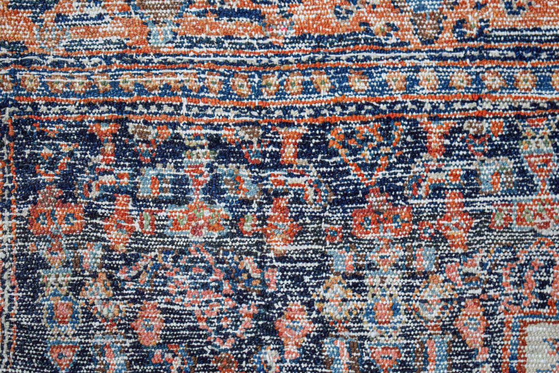 A vintage Persian rug featuring a detailed floral pattern in shades of blue, orange, and cream.