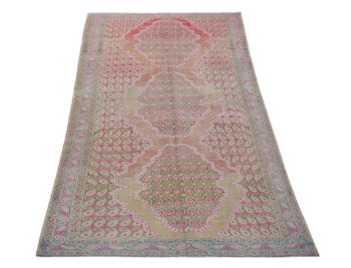 A vintage Persian Senneh rug featuring a repeating paisley pattern in pink and beige tones.