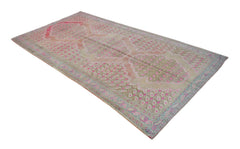 A vintage Persian Senneh rug featuring a repeating paisley pattern in pink and beige tones.