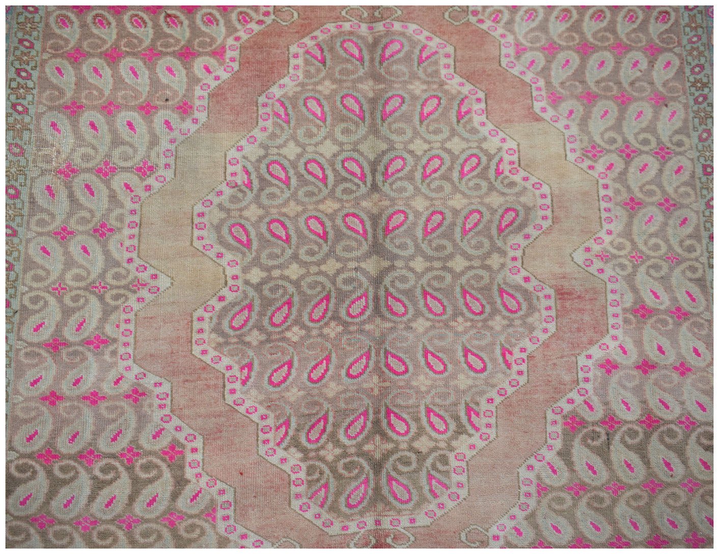 Vintage Persian Senneh rug featuring a repeating paisley pattern in pink and beige tones.
