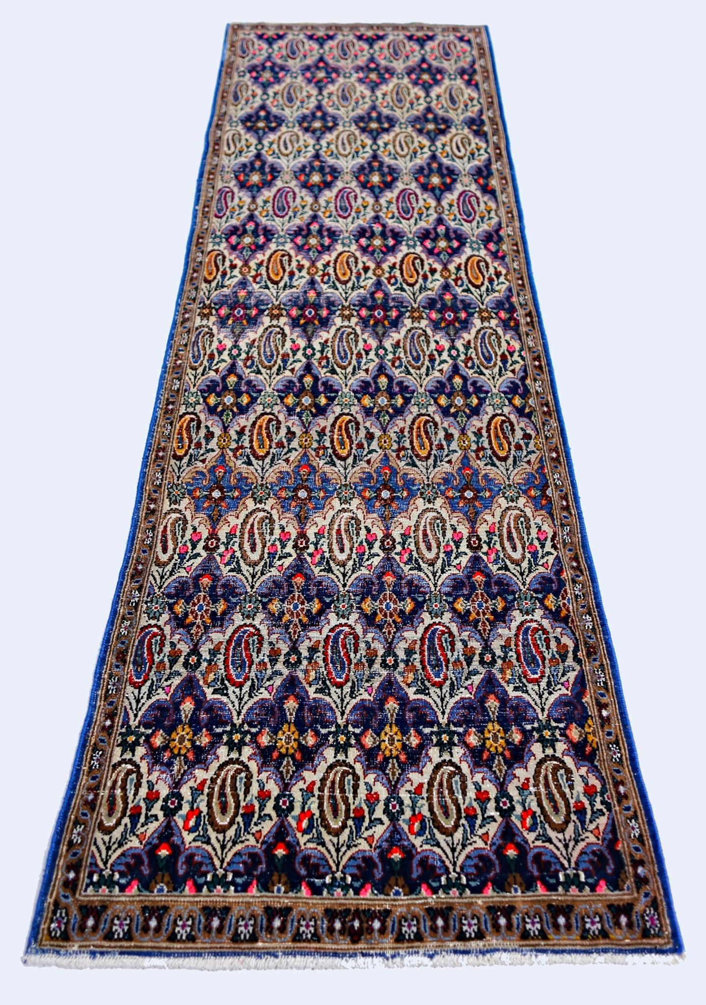 A vintage Persian Senneh runner rug featuring a repeating paisley pattern in vibrant colors.