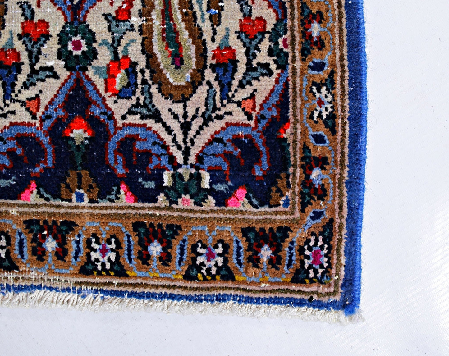 A vintage Persian Senneh runner featuring intricate floral patterns in blue, red, and tan wool.