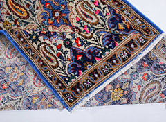 A vintage Persian Senneh runner with a folded corner revealing its intricate floral and paisley pattern.