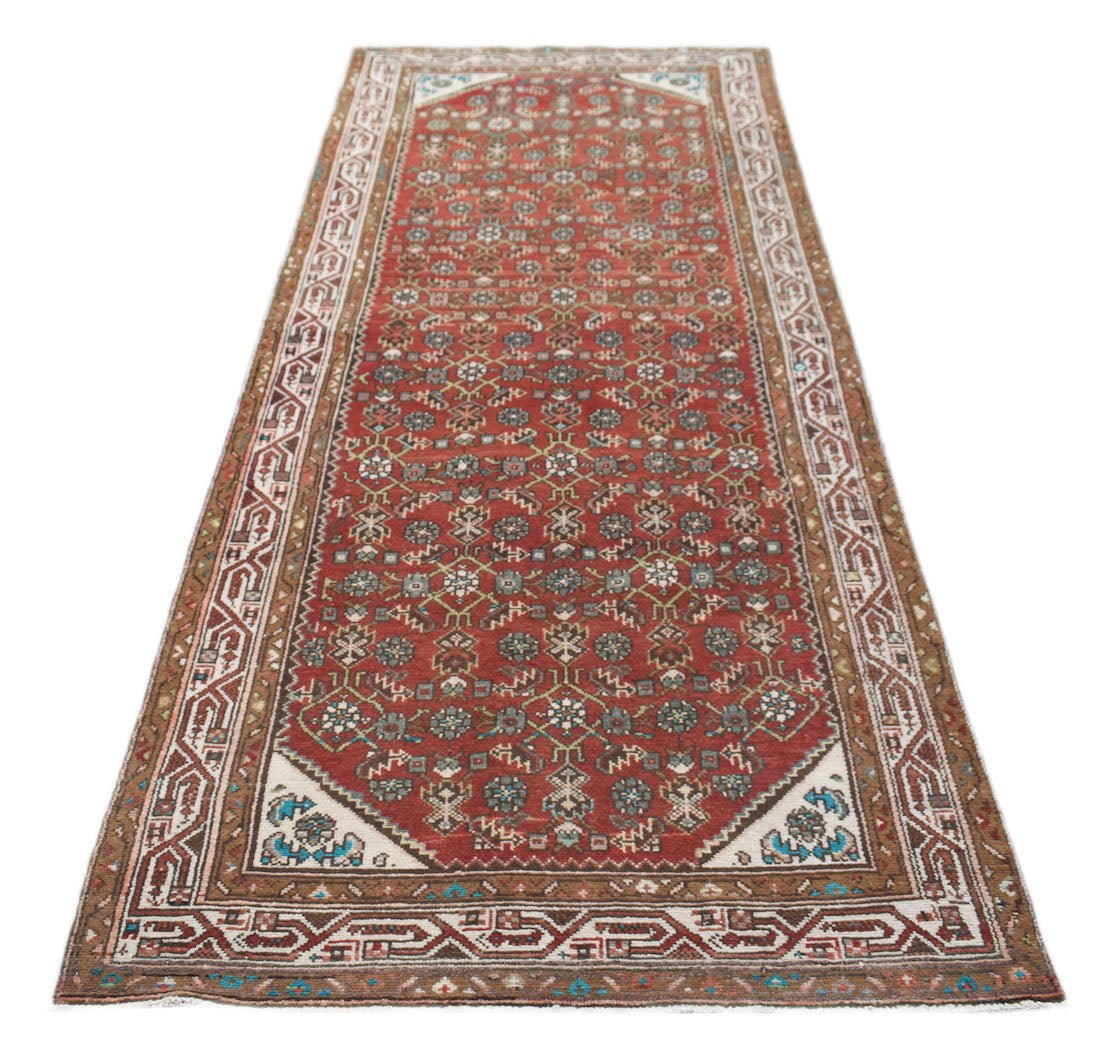 A vintage Persian Senneh runner featuring a red field with intricate geometric floral patterns.