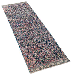 A vintage Persian Senneh runner rug featuring a dark blue field with intricate floral patterns.