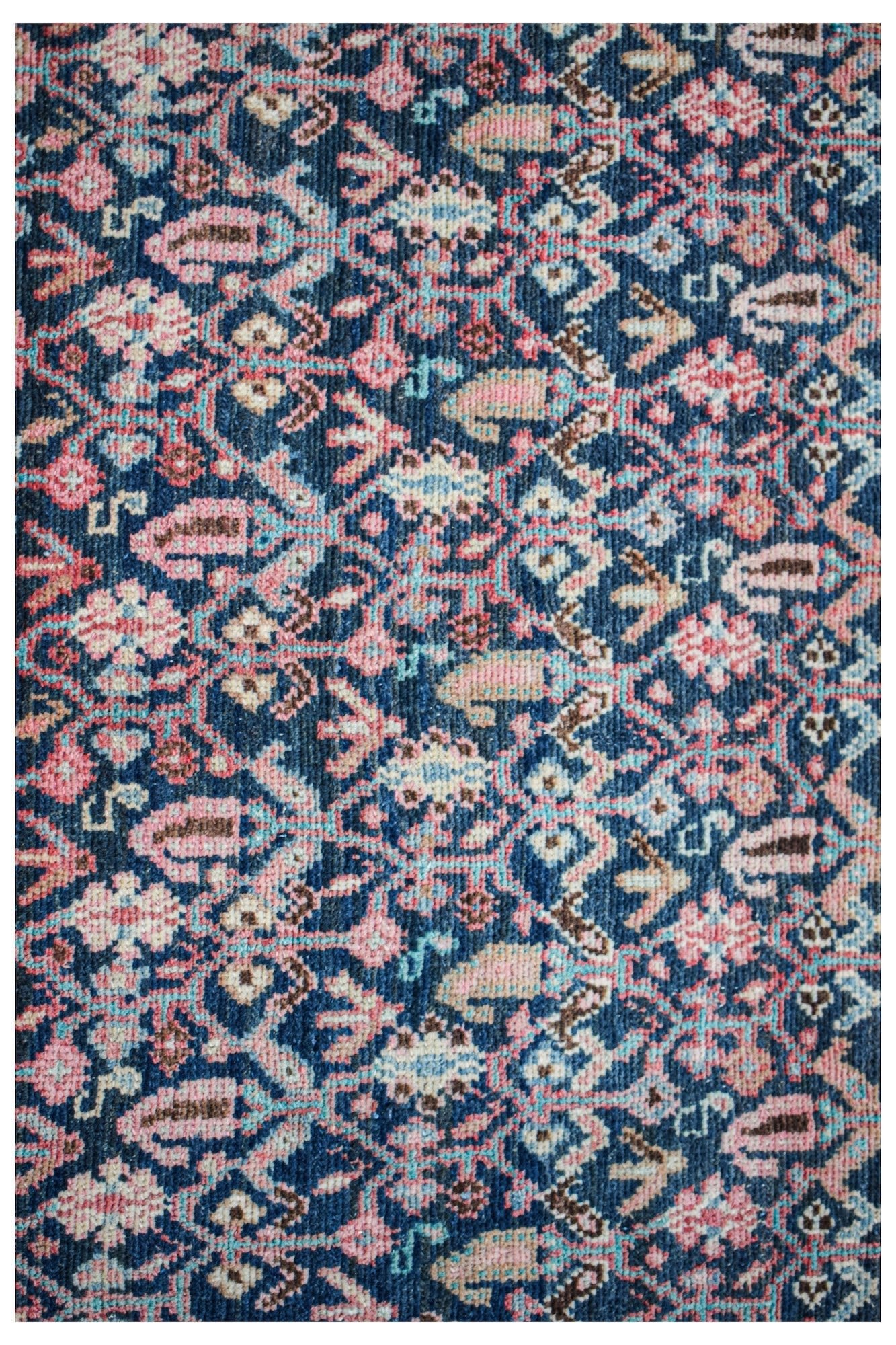 A vintage Persian Senneh runner featuring an intricate floral pattern in blue, pink, and cream.