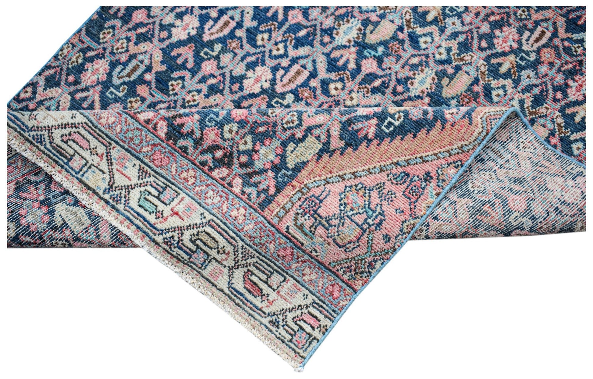 A vintage Persian Senneh runner featuring a blue and pink floral pattern with a folded corner.