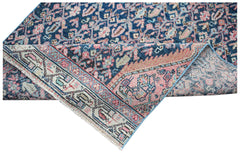 A vintage Persian Senneh runner featuring a blue and pink floral pattern with a folded corner.