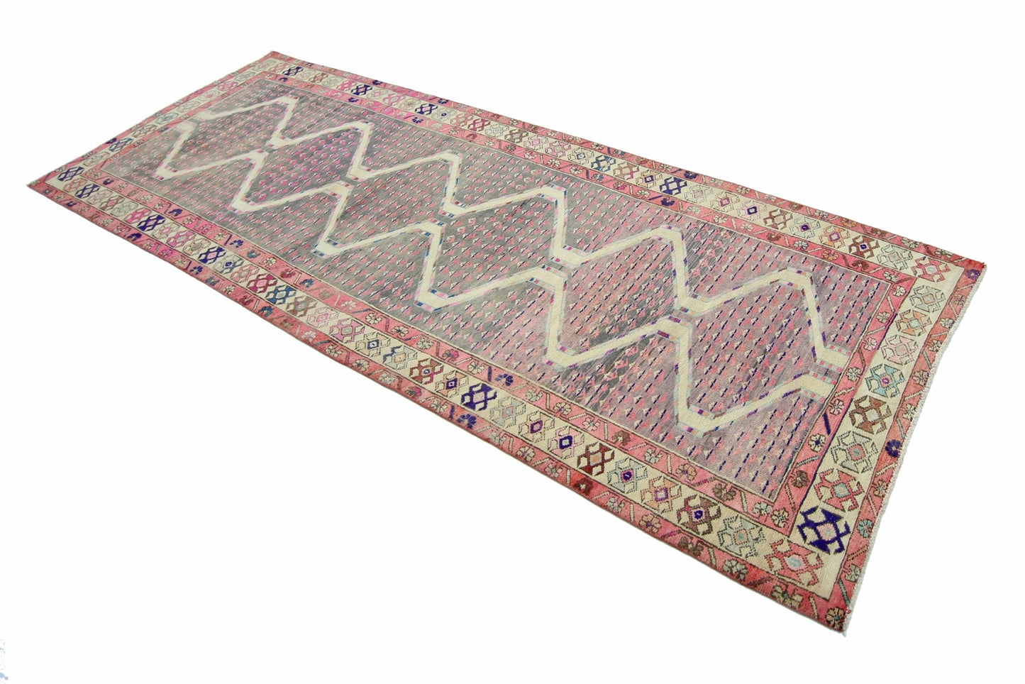 A vintage Persian Senneh runner featuring a pink and grey zigzag diamond pattern on a wool pile.