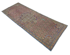 A vintage Persian Senneh runner featuring a geometric pattern in pink, blue, and cream tones.
